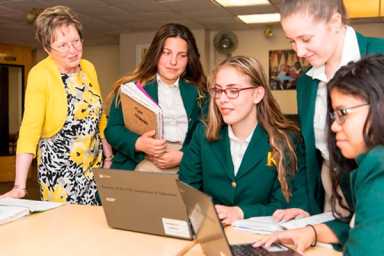 picture of bishop kearney high school students sitting at a table in green uniforms