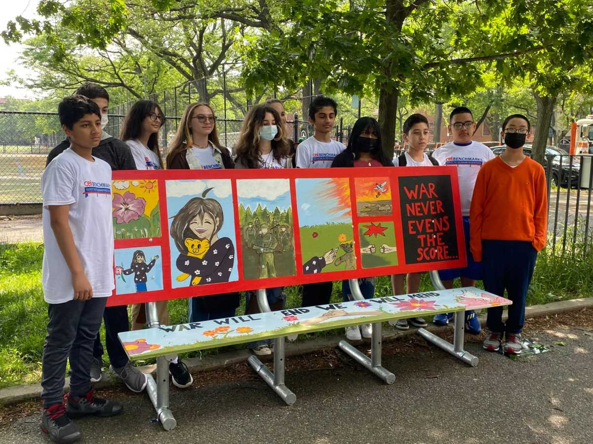 Students stand around mural they created on benches