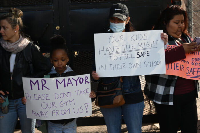 Following the city's decision to use public school gyms as temporary emergency shelters, parents and students protest outside the facility.