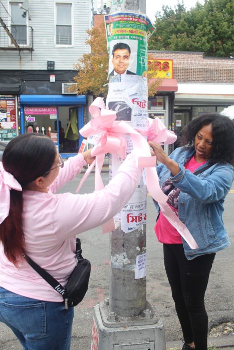 people tying breast cancer awareness month ribbons