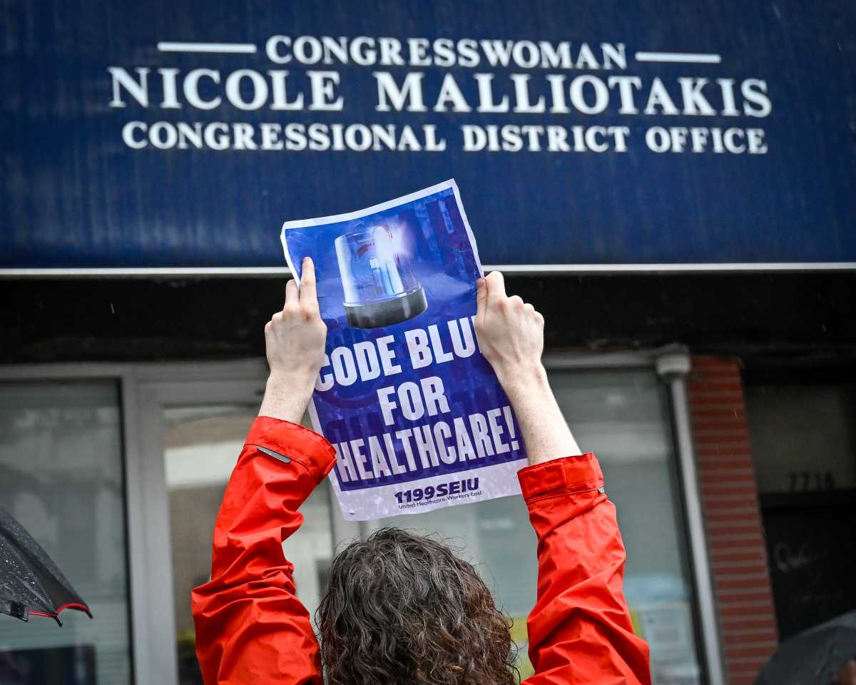 person holding up sign at malliotakis big beautiful bill rally