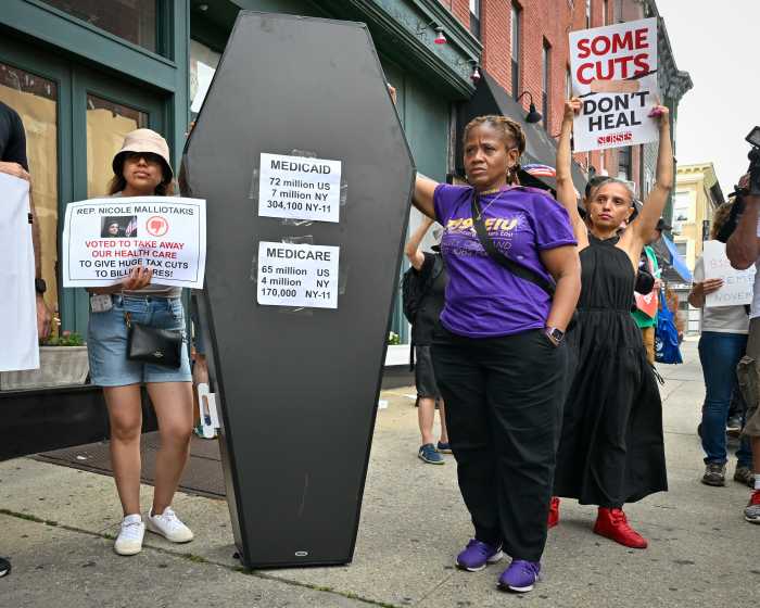 people at healthcare rally pose with prop coffin