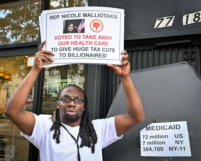 man holding sign criticizing malliotakis