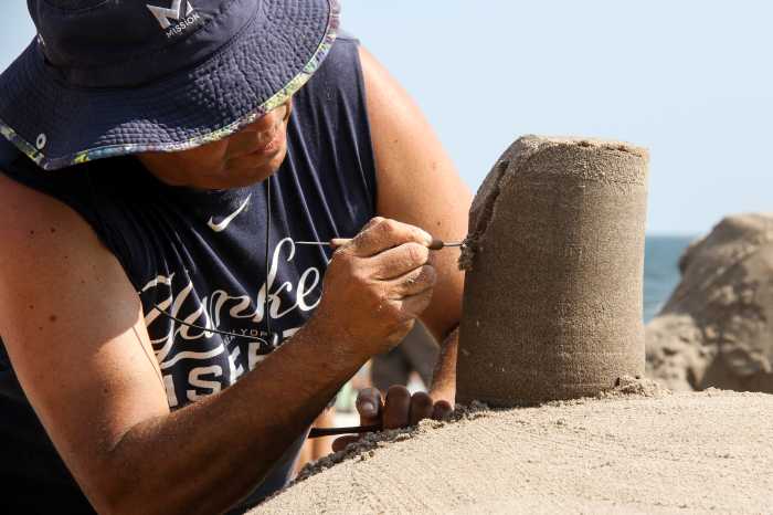 close up of man using tool on sand sculpture