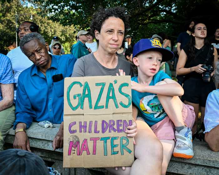 woman holding sign that says gaza's children matter