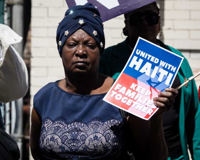 a woman holding a sign that says 'united with haiti keep families together'